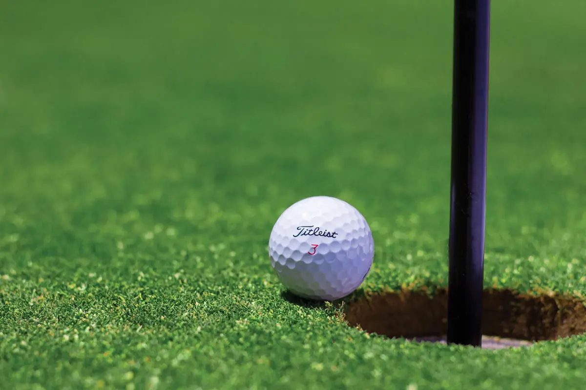 A golf ball resting at the lip of the hole